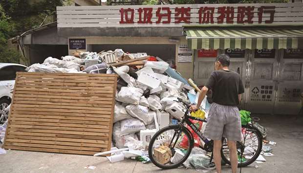 In this photo taken on July 11, 2019, a man looks at piled up garbage at a housing complex in the former French concession in Shanghai. Shanghai on July 1 launched Chinau2019s most ambitious garbage separation and recycling programme ever, as the country confronts a rising tide of trash created by increasingly consumptive ways. But the programme is the talk of Chinau2019s biggest city for other reasons as well: confusion over rules and fines for infractions, and thousands of volunteers inspecting citizensu2019 private garbage each day.