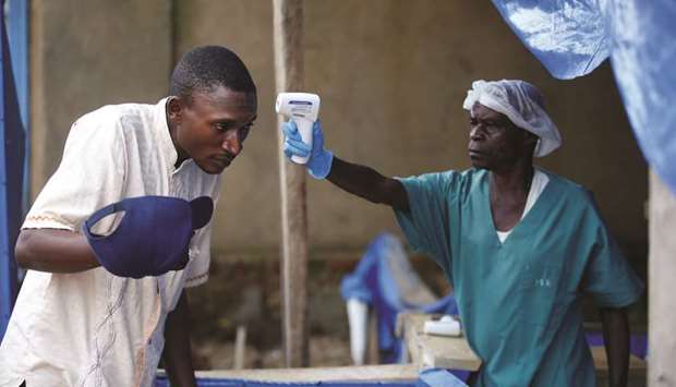 FILE PHOTO: A health worker measures the temperature of a man entering the ALIMA (The Alliance for International Medical Action) Ebola treatment centre in Beni, in the Democratic Republic of Congo, on April 1, 2019.