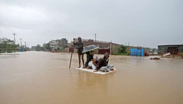Villagers use a makeshift raft to cross a flooded area on the outskirts of Agartala, India