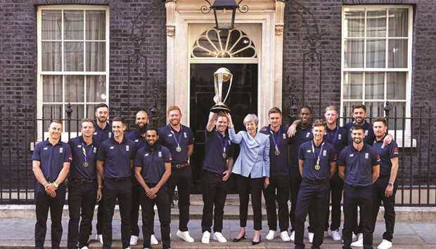 Britainu2019s Prime Minister Theresa May lifts the World Cup trophy with England captain Eoin Morgan in the presence of rest of the team for a photograph outside 10 Downing Street in London on Monday. (AFP)