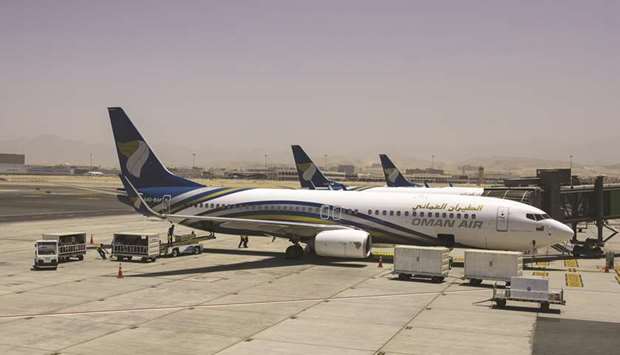 A Boeing 737-800 aircraft, operated by Oman Air, stands beside the passenger terminal at Muscat International Airport.