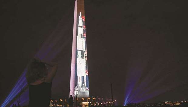 People look at an image of a Saturn V, the rocket that sent Apollo 11 into orbit on July 16, 1969, projected on the Washington monument in Washington, DC on Tuesday night in honour of the 50th anniversary of Apollo 11 space flight.