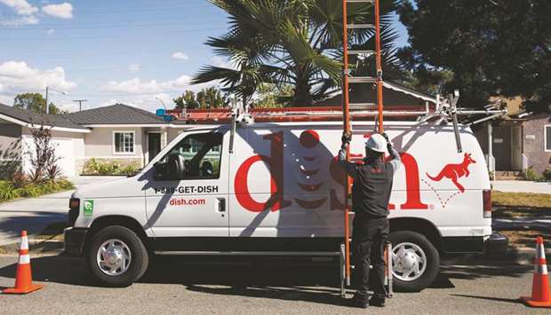 A Dish Network Corp field service specialist carries a ladder after installing a satellite television system at a residence in Paramount, California.