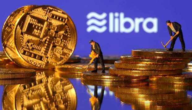 Small toy figures are seen on representations of virtual currency in front of the Libra logo in this illustration picture, June 21, 2019