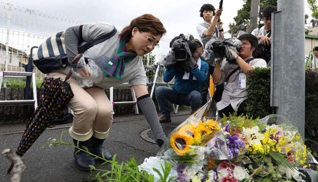 Residents place flowers for victims of a fire which hit the Kyoto Animation studio building the day before, killing 33 people, in Kyoto