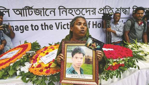 Masuda Begum, mother of Jakir Hossain Shawon, a worker of Holey Artisan Bakery cafe who died in hospital days after the siege at the cafe, holds a photo of her son on the third anniversary of the cafe attack in Dhaka yesterday.