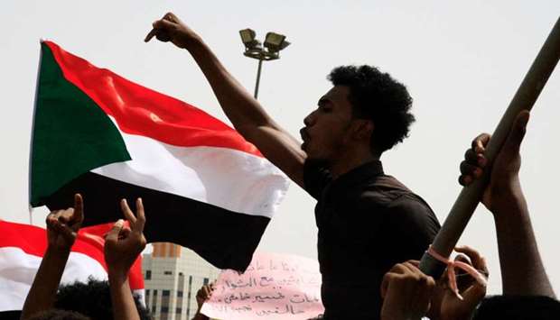 A Sudanese protester chants slogans as others wave national flags in the capital Khartoum's Green Square on July 18, as they honour comrades killed in the months-long protest movement that has rocked the country.