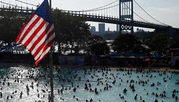 A US flag flies overhead as people enjoy the Astoria Pool on a hot afternoon in the borough of Queens, New York City