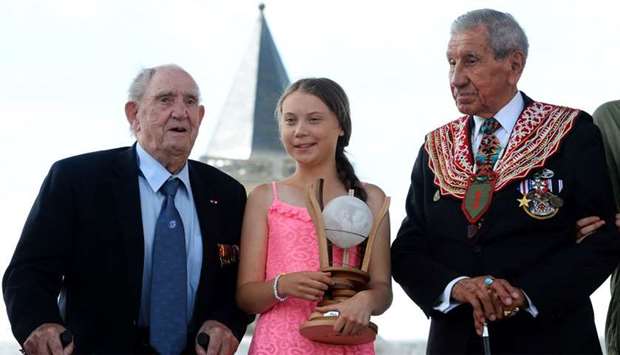 Swedish climate activist Greta Thunberg, flanked by WWII veteran and native American Charles Norman Shay (R), sponsor of the Freedom Award, and French WWII veteran Leon Gautier, poses with the Normandy 'Freedom prize' during the award ceremony