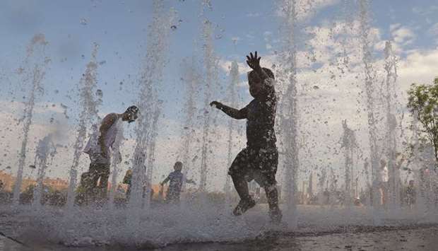 Children play in a water feature in Domino Park in Brooklyn, New York City.