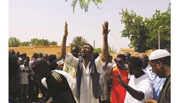 Relatives of three Sudanese men riddled with bullets mourn next to the corpses in the city of Omdurman across the River Nile from Khartoum, yesterday.