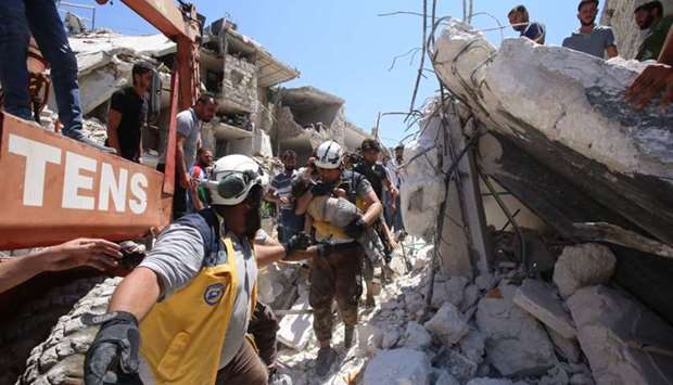 Members of the Syrian civil defence, known as the White Helmets, pull out an injured but alive child from under the rubble following a Russian air strike on Maaret al-Numan in Syria's northwestern Idlib province