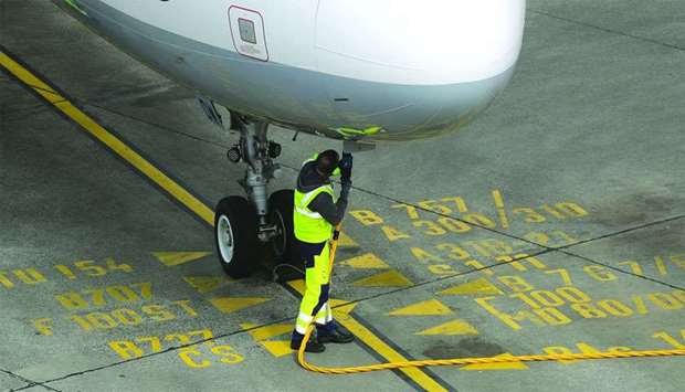 A ground crew member connects a fuel hose to an Airbus A321 aircraft, operated by Deutsche Lufthansa, at Tegel airport in Berlin. Even though oil prices fluctuate with supply risks, lower global economic growth is expected to put downward pressure on oil demand, IATA says.