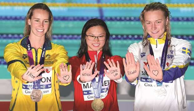 (From left) Silver medallist Sarah Sjostrom of Sweden, gold medallist Margaret Macneil of Canada and bronze medallist Emma Mckeon of Australia stand on the womenu2019s 100m butterfly podium with a message of support for Japanu2019s Rikako Ikee on their palms at the 2019 World Championships in Gwangju, South Korea, yesterday. (AFP)