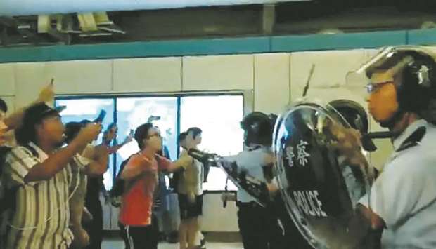 Anti-extradition bill demonstrators argue with police after they were attacked by men in white T-shirts and face masks, at a train station in Hong Kong, China, in this still image obtained from a social media live video.