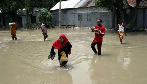 People cross a flooded road in Jamalpur, Bangladesh
