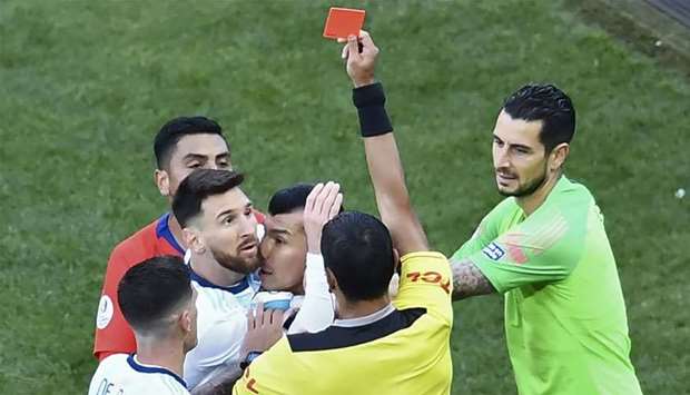 Paraguayan referee Mario Diaz de Vivar shows the red card to Argentina's Lionel Messi and Chile's Gary Medel as they have a physical encounter during the Copa America football tournament third-place match at the Corinthians Arena in Sao Paulo, Brazil