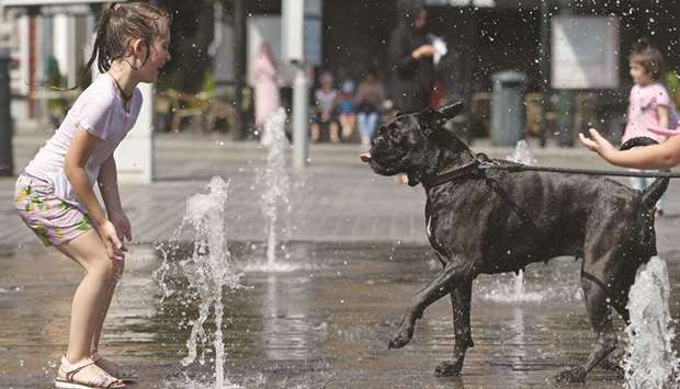 A girl plays with her dog in a water fountain in Brussels.