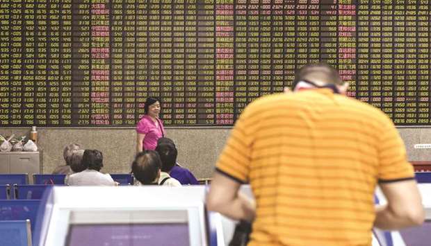 An investor stands at a trading terminal in front of an electronic stock board at a securities brokerage in Shanghai. Chinese equities gained 0.5% to 2,937.36 points yesterday.