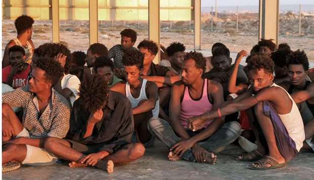 Rescued migrants sit on the coast of Khoms, some 100 kilometres from Tripoli