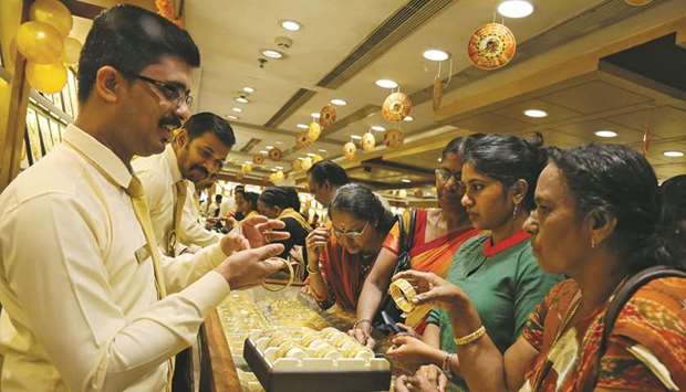 A salesman shows gold bangles to customers inside a jewellery showroom in Kochi. Gold buying stagnated in India as local rates soared, though some investors used temporary price dips to buy, hoping to cash in on a further leg up.