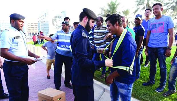 Officials helping pedestrians wear a reflecting jacket during an awareness programme.
