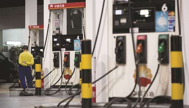 A Petrochina Co employee stands next to gas pumps at one of the companyu2019s gas stations in Beijing.