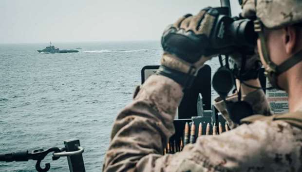 A US Marine observes an Iranian fast attack craft from USS John P. Murtha during a Strait of Hormuz 