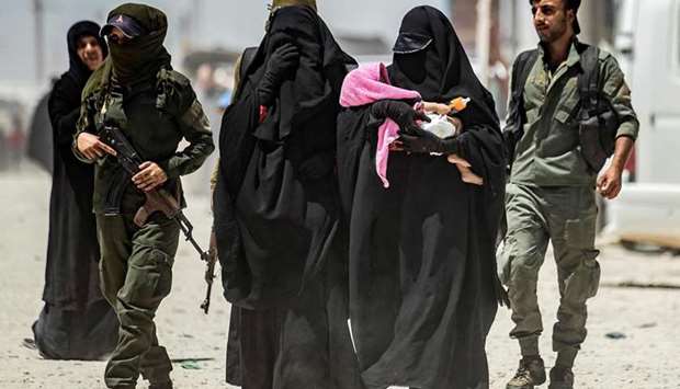 An internal security patrol escorts women, reportedly wives of Islamic State (IS) group fighters, in the al-Hol camp in al-Hasakeh governorate in northeastern Syria, on July 23