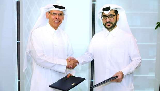 Woqod and Al Meera officials shake hands after signing the MoU to operate and manage current and prospective Woqodu2019s Sidra Convenience Stores.