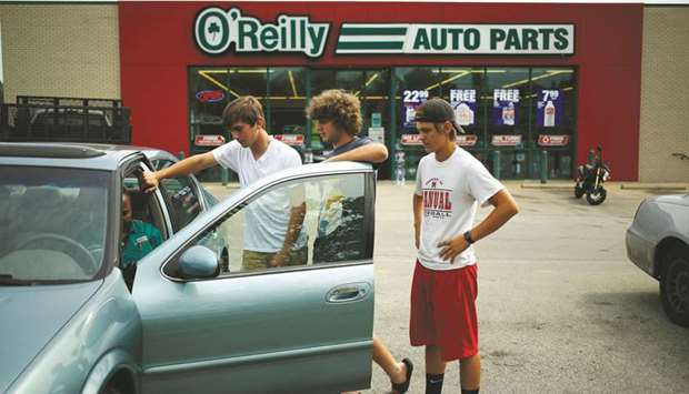 Customers watch as an employee investigates a check engine light on their vehicle outside an Ou2019Reilly Automotive auto parts store in Louisville, Kentucky.