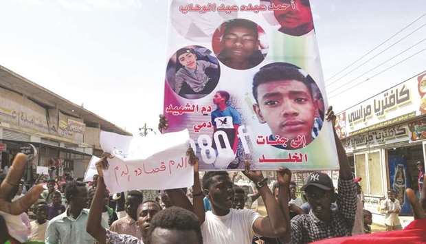Sudanese protesters march with a poster bearing the portraits of victims, who were shot dead for protesting against a shortage of bread, during a demonstration in the central city of Al-Obeid yesterday.