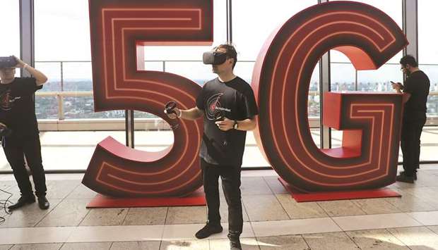 A man uses a virtual-reality headset in front of a 5G logo during the launch of Vodafone Groupu2019s 5G wireless network in London yesterday. Nick Jeffery, chief executive of Vodafone UK, said offering unlimited data plans to both consumer and business customers would revolutionise the mobile market.