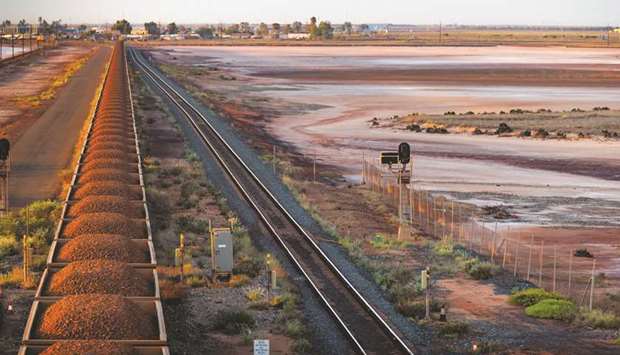 A freight train carrying iron ore travels along a rail track towards Port Hedland, Australia.