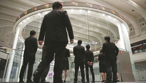 Visitors watch share prices at the Tokyo Stock Exchange. The Nikkei 225 closed down 0.5% to 21,638.16 points yesterday.