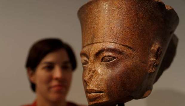 Laetitia Delaloye, head of antiquities of Christie's, poses for a photograph with an Egyptian brown quartzite head of the God Amen prior to its' sale at Christie's auction house in London