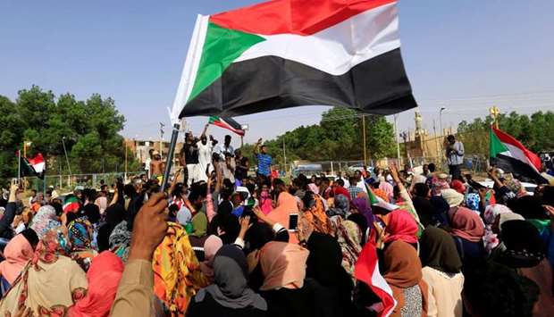 Sudanese people chant slogans and wave their national flag as they celebrate, after Sudan's ruling military council and a coalition of opposition and protest groups reached an agreement to share power during a transition period leading to elections, along the streets of Khartoum