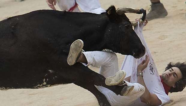 A participant is tossed by a heifer bull during the first bullrun of the San Fermin festival in Pamplona, northern Spain