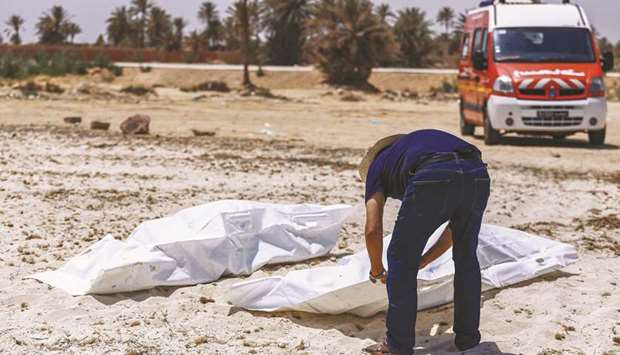 A representative of the Tunisian Red Crescent association checks bodies recovered from a boat carrying 86 migrants that capsized off the coast, as they lie on a beach in Aghir in the southern island of Djerba, yesterday.