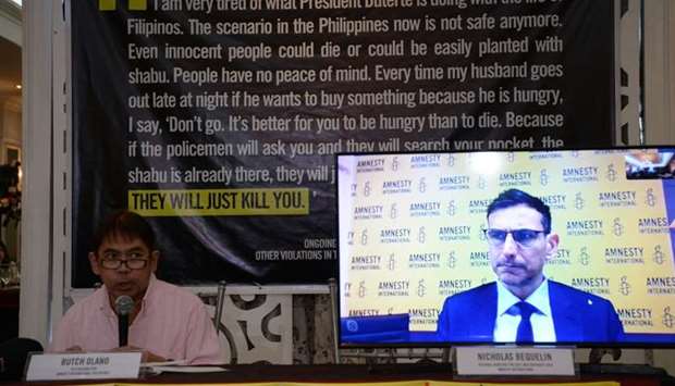 Butch Olano (L), Amnesty International section representative speaks while Nicholas Bequelin (video screen) Amnesty International Regional Director for East and Southeast Asia, listen during a press conference in Manila