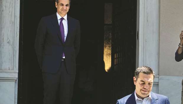 Mitsotakis watches his predecessor Tsipras leaving the Maximos Mansion after their meeting.