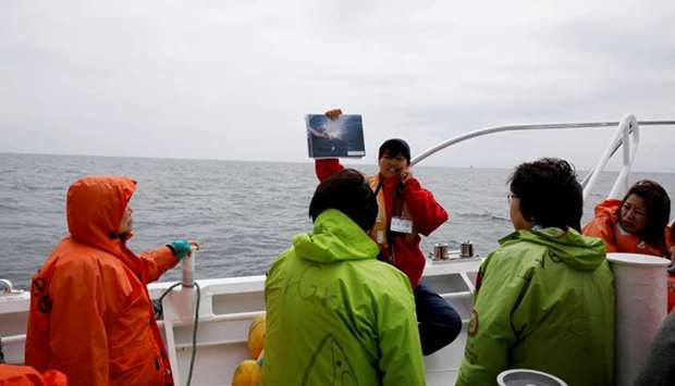 A staff on a whale watching tour boat explains about whales to tourists on the boat in the sea near Rausu, Hokkaido, Japan, July 1.