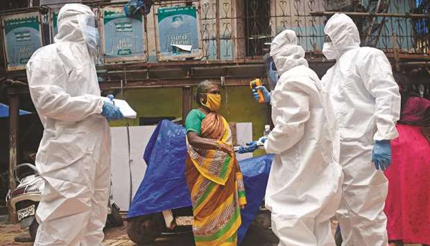 Medical volunteers wearing personal protective equipment (PPE) take temperature reading of a woman as they conduct a door-to-door medical screening inside Dharavi slums to fight against the spread of coronavirus, in Mumbai yesterday.