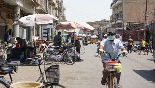 A man wearing a face mask rides a bicycle along the Al-Sadriya Market in the Iraqi capital Baghdad amid the novel coronavirus pandemic crisis