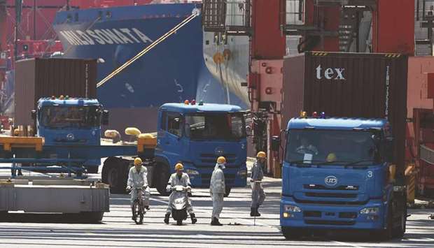 Trucks are seen transporting containers from a pier in Tokyou2019s port. Japanu2019s economy is forecast to contract 5.3% this fiscal year, a July 3-9 poll of over 30 economists shows, the most it has shrunk since comparable data became available in 1994. It will rebound 3.3% next year, according to the poll.
