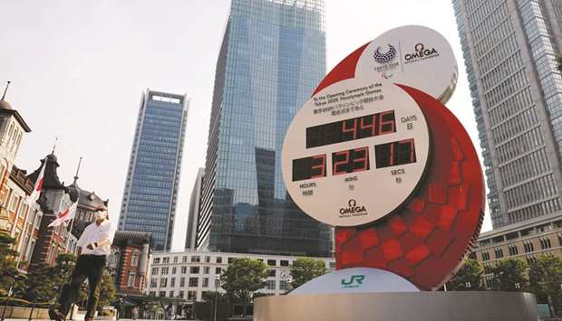 In this June 4, 2020, picture, a man wearing a protective mask walks past a countdown clock for the Tokyo Olympic Games in Tokyo, Japan. (Reuters)