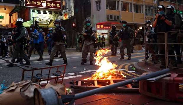 Riot police walk past a fire set by anti-national security law protesters during a march at the anniversary of Hong Kong's handover to China from Britain in Hong Kong