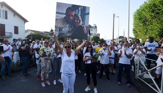 Veronique Monguillot, wife of bus driver Philippe Monguillot, declared brain dead after being attacked for refusing to let aboard a group of people who were not wearing face masks, holds a picture of her husband in front of Bayonne's hospital during a white march in Bayonne, southwestern France