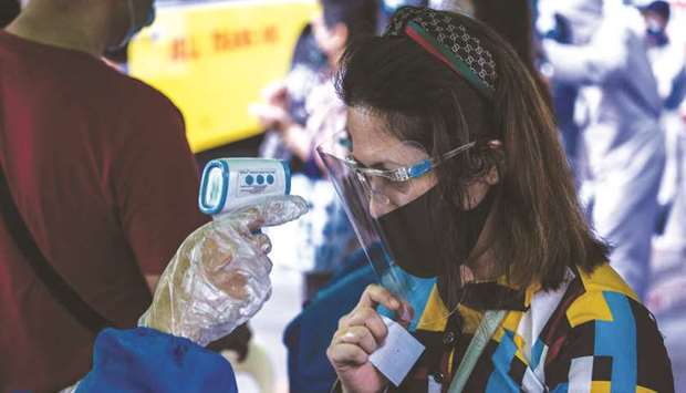 A passenger has her body temperature taken before boarding a bus in Manila.