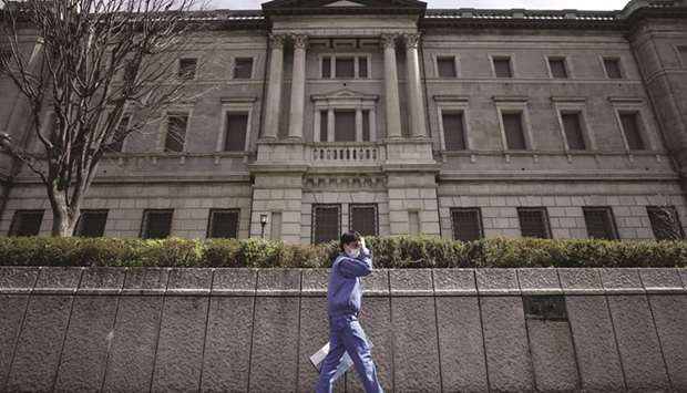 A pedestrian wearing a protective mask walks past the Bank of Japan headquarters in Tokyo. A new BoJ lending programme for stock-fund investors is attracting scant demand, raising questions about the central banku2019s latest attempt to ease the side effects of its massive stimulus policy.